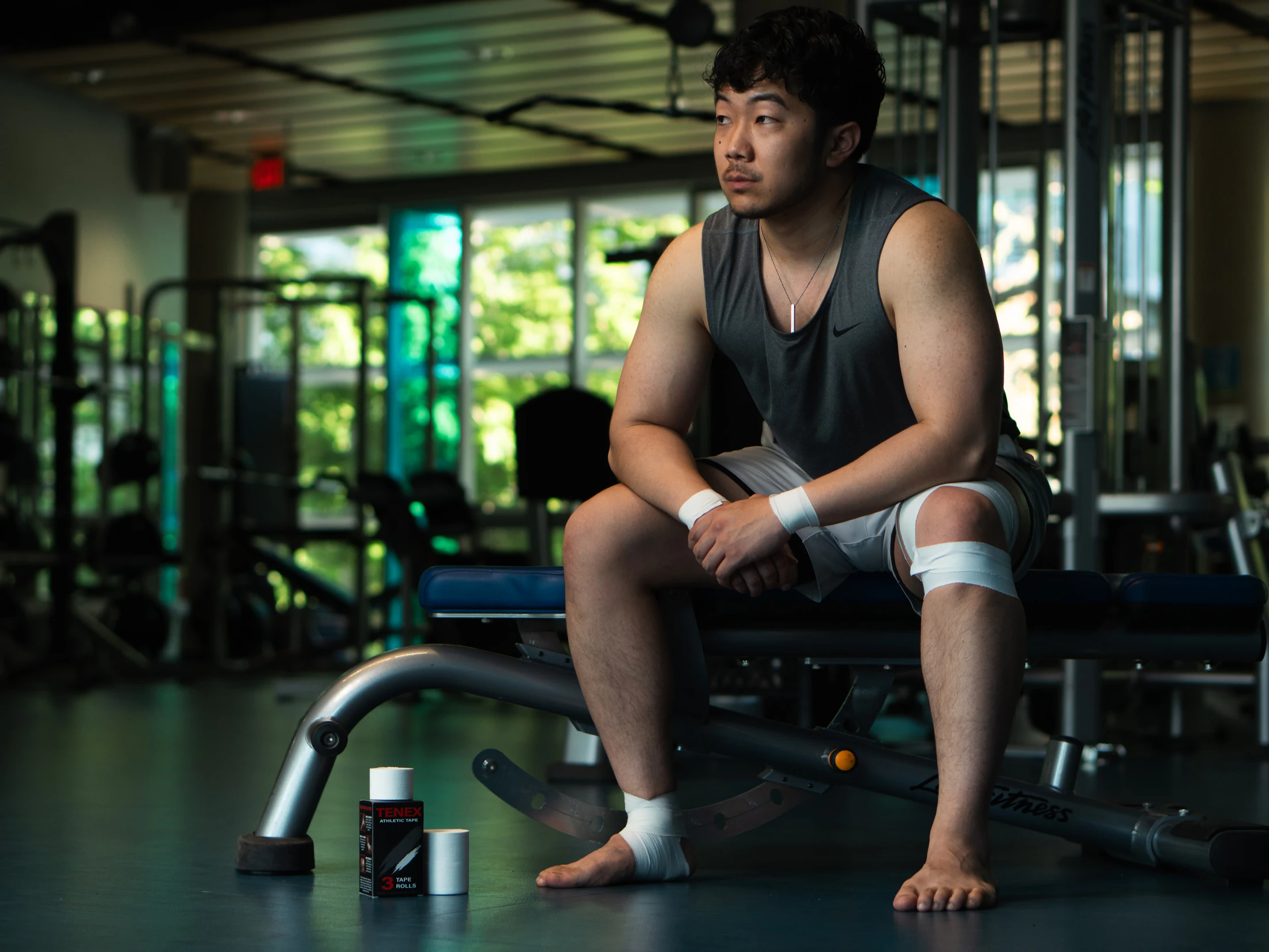 Athlete sitting on a bench with taped wrists and knee