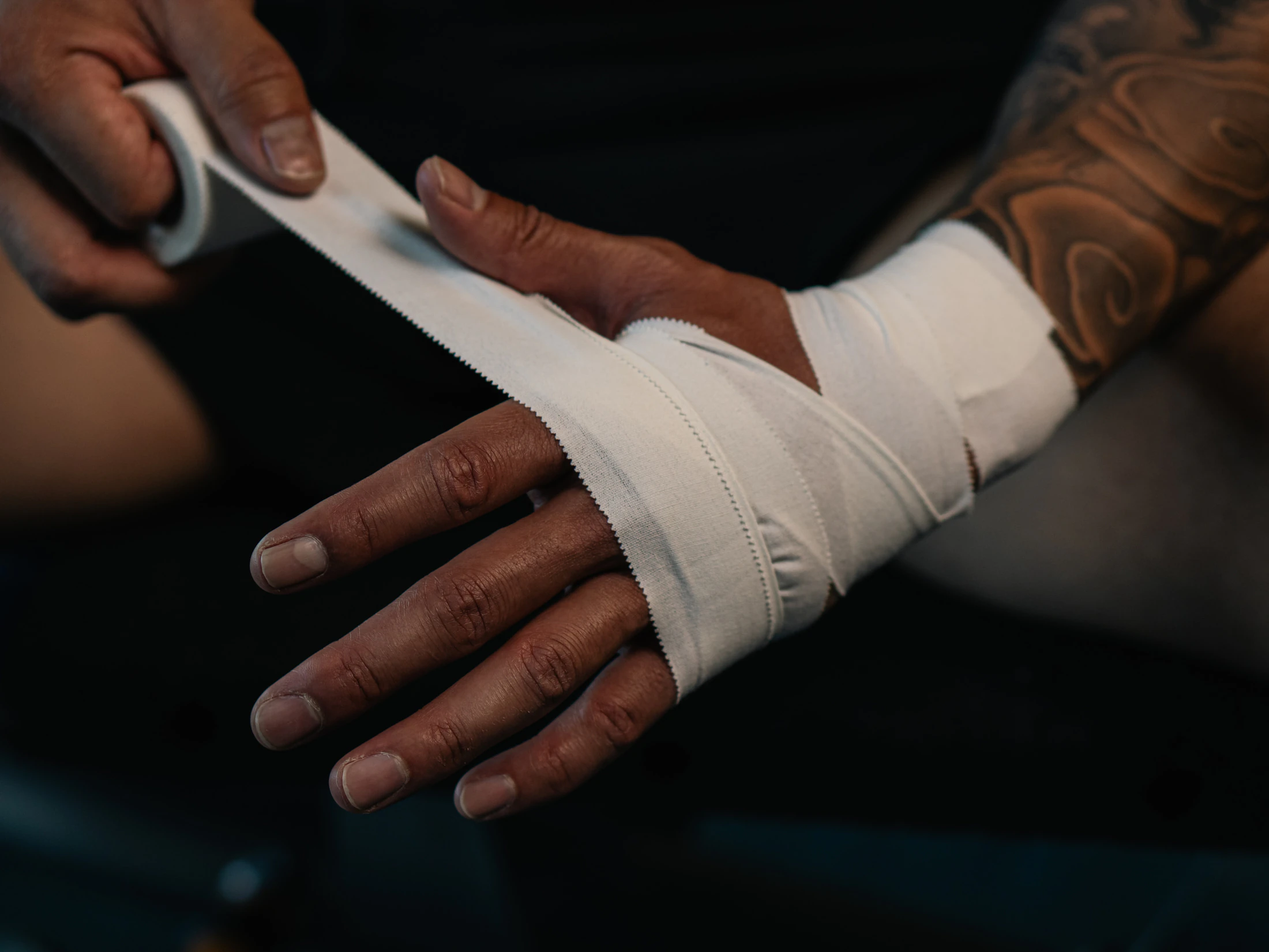 Hands wrapping tape across a palm and wrist